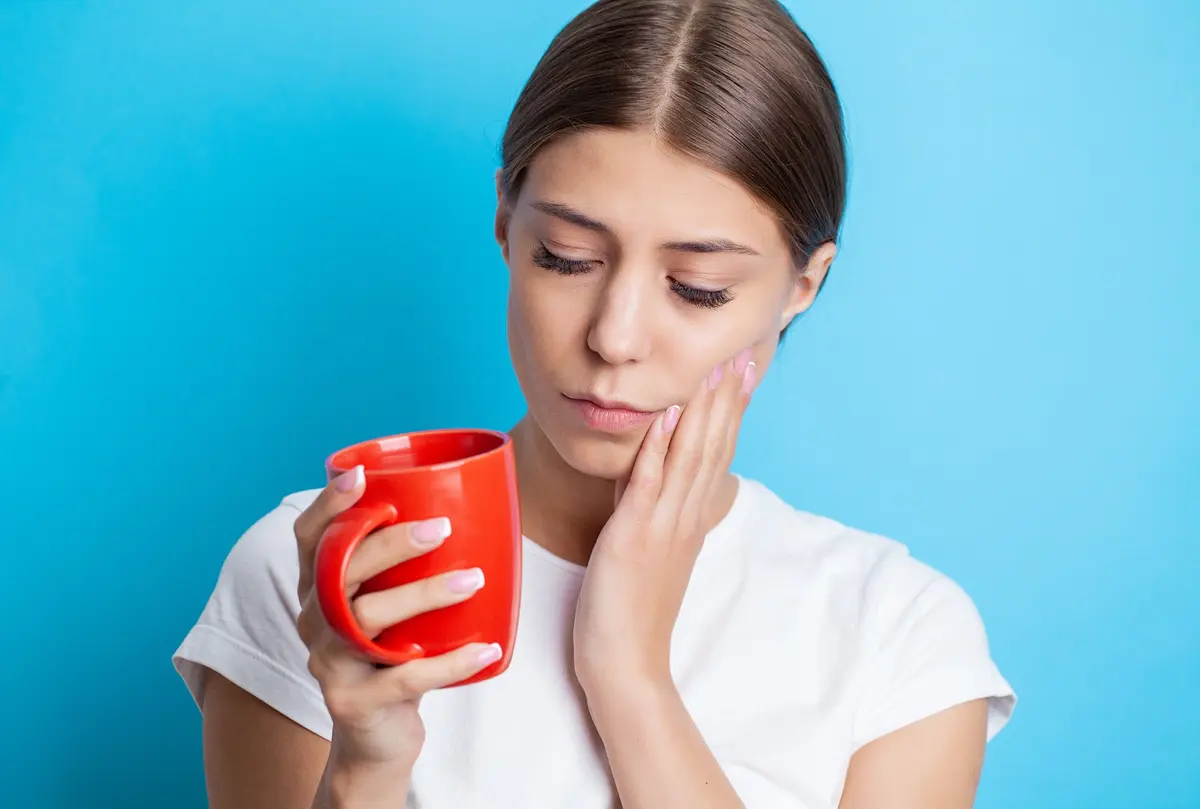 Mujer con dolor dental al beber algo caliente por sensibilidad dental