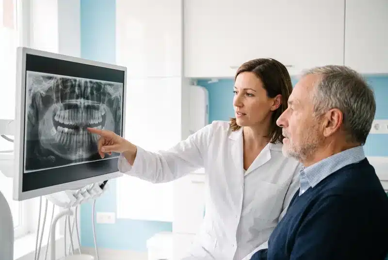 Odontóloga mostrando a un paciente su radiografía para planificar una prótesis híbrida